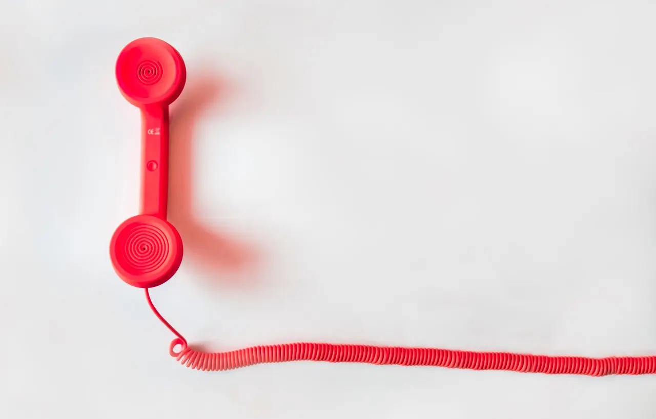 Rotes altmodisches Wandtelefon an einer weißen Wand